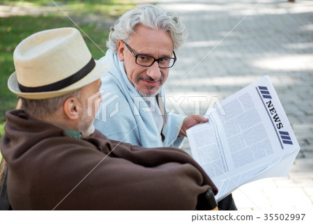 Joyful senior male friends reading newspaper 35502997