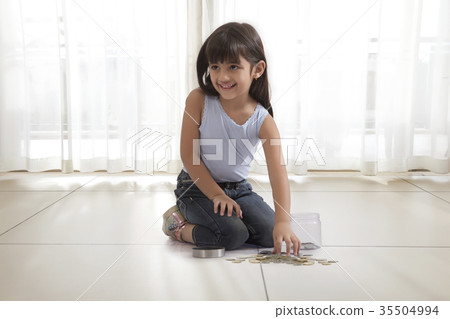 little girl with coin box and coins on floor 35504994