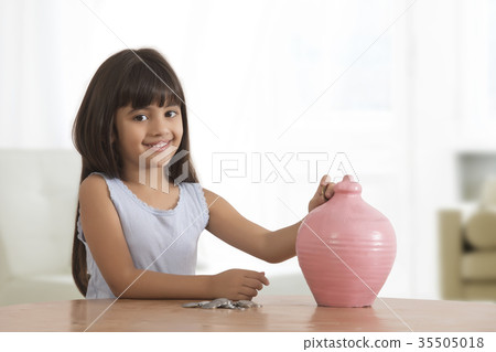 Portrait of little girl inserting coins in clay piggy bank Portrait of little girl inserting coins in clay piggy bank 35505018