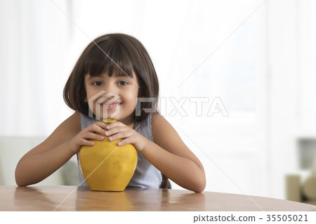 Portrait of smiling little girl holding clay piggy bank Portrait of smiling little girl holding clay piggy bank 35505021