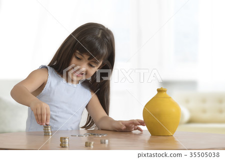 Smiling girl arranging coins on table Smiling girl arranging coins on table 35505038