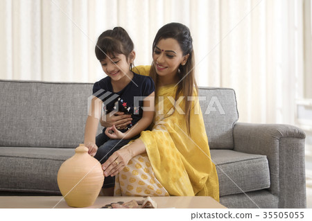 Mother and daughter putting coins in piggy bank Mother and daughter putting coins in piggy bank 35505055