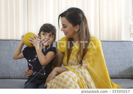 Girl shaking clay piggybank and mother looking at her 35505057