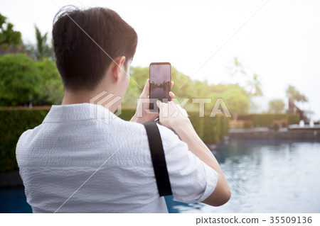 Young man tourist taking photos with cell phone 35509136