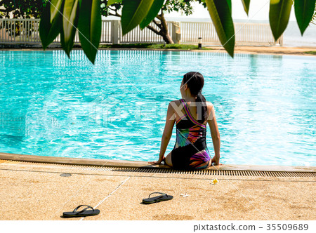 Rear view woman sitting on edge of swimming pool 35509689