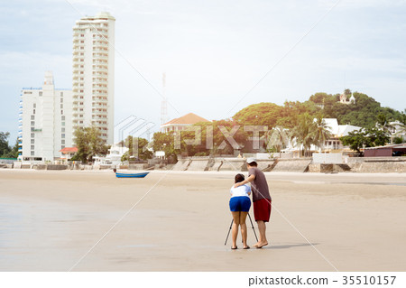 Couple taking picture using tripod on the beach Couple taking picture using tripod on the beach 35510157