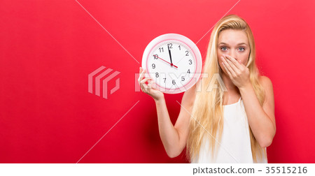 Woman holding clock showing nearly 12 35515216