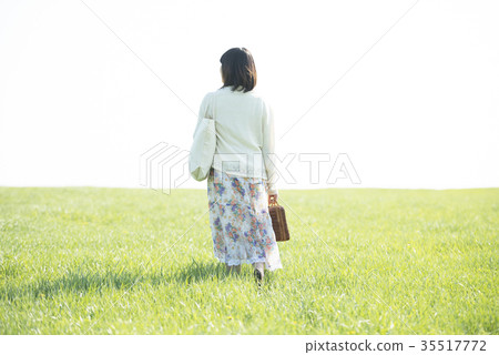 A rear view of a woman walking along the grassland A rear view of a woman walking along the grassland 35517772