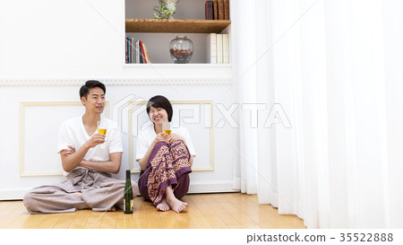 A couple sitting on the floor and tilting the glass A couple sitting on the floor and tilting the glass 35522888