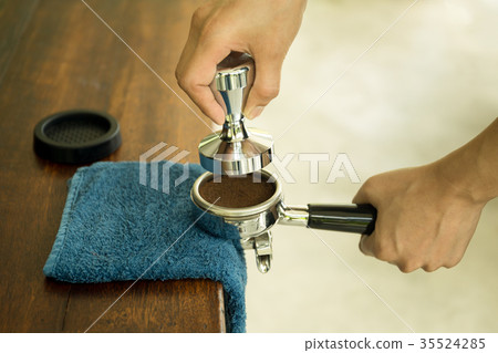 Barista pressing ground coffee into tamper 35524285
