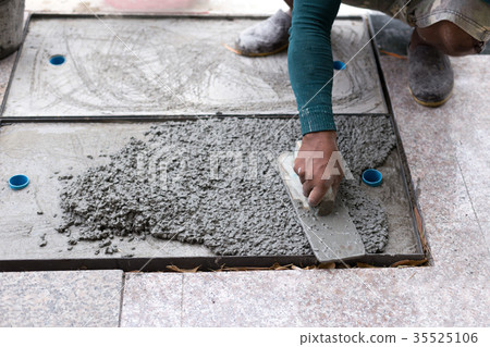 Worker leveling cement of drain hose with trowel 35525106