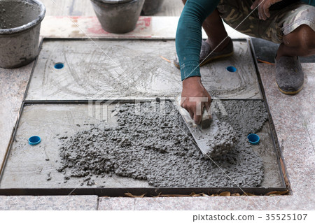 Worker leveling cement of drain hose with trowel 35525107