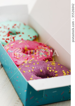 Colorful donuts in box on white wooden background Colorful donuts in box on white wooden background 35526842