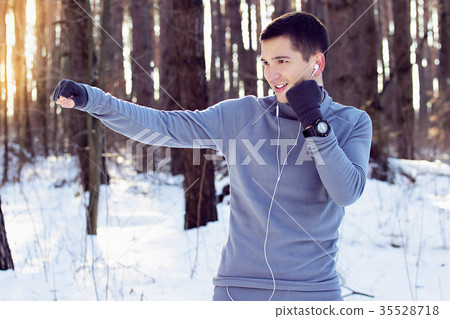 Sports man doing boxing exercise in forest. Winter Sports man doing boxing exercise in forest. Winter 35528718