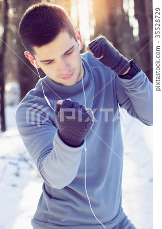 Sports man doing boxing exercise in forest. Winter Sports man doing boxing exercise in forest. Winter 35528729
