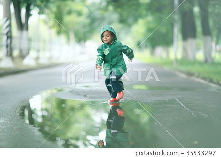 cheerful little girl walks and jumps in puddles in the rain cheerful little girl walks and jumps in puddles in the rain 35533297