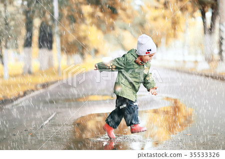 cheerful little girl walks and jumps in puddles in the rain cheerful little girl walks and jumps in puddles in the rain 35533326