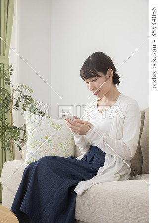 A woman looking at her smartphone in the living room A woman looking at her smartphone in the living room 35534036