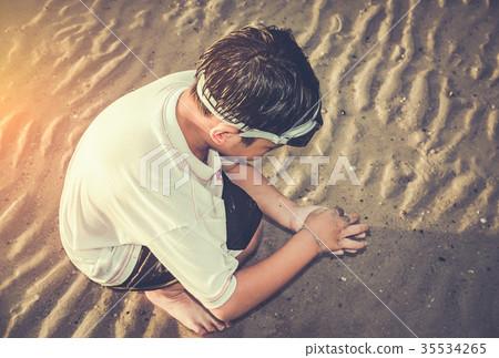 Asian child has fun digging in the sand. Asian child has fun digging in the sand. 35534265