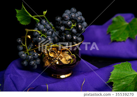 Red wine grapes in golden cup on violet Red wine grapes in golden cup on violet 35539270