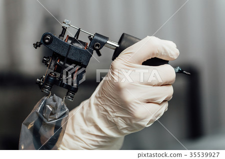 Close-up tattoo artist holding tattoo machine on Close-up tattoo artist holding tattoo machine on 35539927