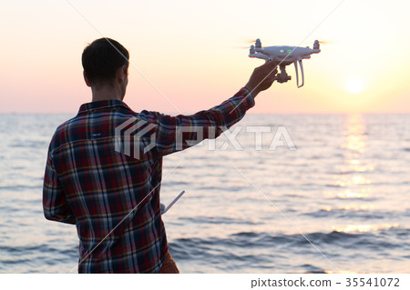 man launches a drone on the beach man launches a drone on the beach 35541072