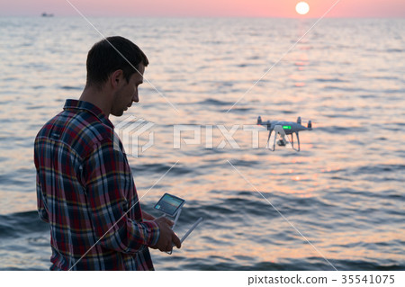 man launches a drone on the beach 35541075