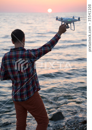 man launches a drone on the beach man launches a drone on the beach 35541108
