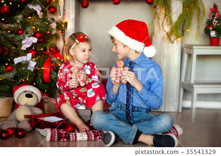 Boy and girl sit on the floor under the Christmas 35541329