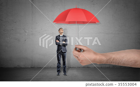 A small businessman stands looking up on a red 35553004