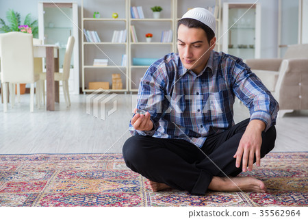 Young muslim man praying at home Young muslim man praying at home 35562964