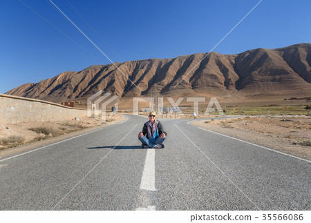 Woman sitting with cross leg on the road. Fork in the road. Morocco Woman sitting with cross leg on the road. Fork in the road. Morocco 35566086
