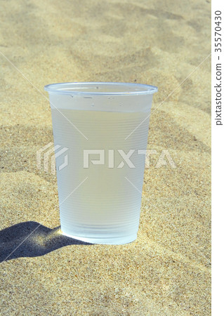 Plastic glass with water standing on the sand Plastic glass with water standing on the sand 35570430