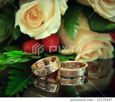 Golden wedding rings with bouquet. Focus on the rings Golden wedding rings with bouquet. Focus on the rings 35570447