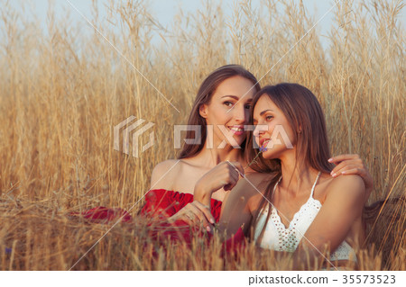 Women sit embracing each other. 35573523