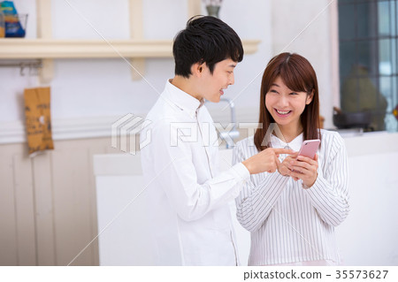 Couple using smartphones Young men and women College students Western-style house 35573627