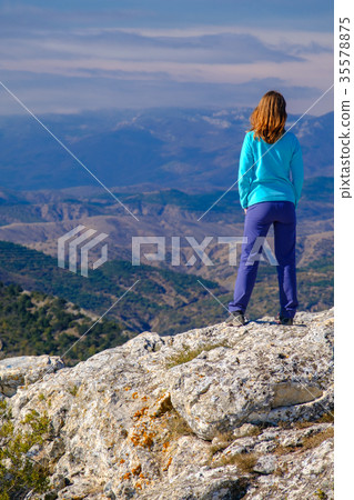 Young woman standing on rocky top of the mountain Young woman standing on rocky top of the mountain 35578875