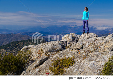 Young woman standing on rocky top of the mountain Young woman standing on rocky top of the mountain 35578879