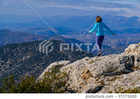 Young woman walking on rocky top of the mountain 35578880