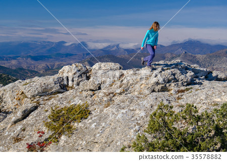 Young woman walking on rocky top of the mountain Young woman walking on rocky top of the mountain 35578882