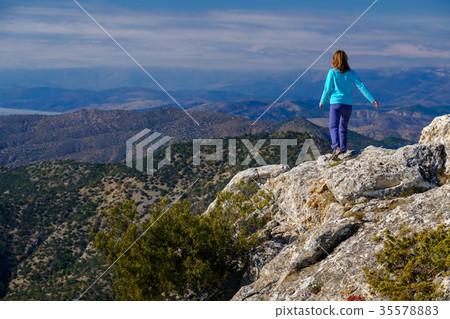 Young woman walking on rocky top of the mountain Young woman walking on rocky top of the mountain 35578883