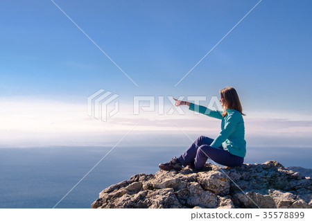 Woman sitting in a rocky top of the mountain Woman sitting in a rocky top of the mountain 35578899