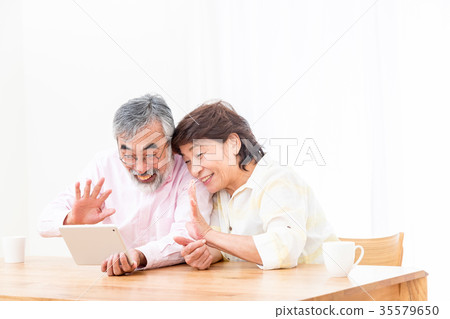 Chatting with a senior silver grandson and videophone to enjoy internet calls with family on tablet Chatting with a senior silver grandson and videophone to enjoy internet calls with family on tablet 35579650