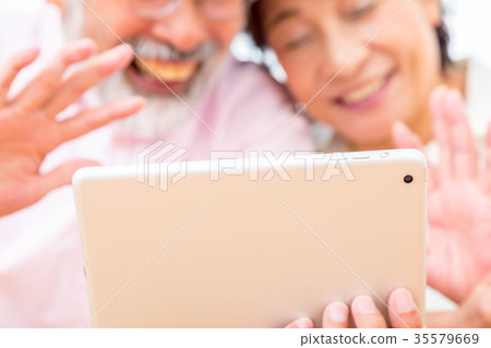 Chatting with a senior silver grandson and videophone to enjoy internet calls with family on tablet 35579669