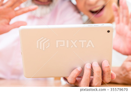 Chatting with a senior silver grandson and videophone to enjoy internet calls with family on tablet 35579670