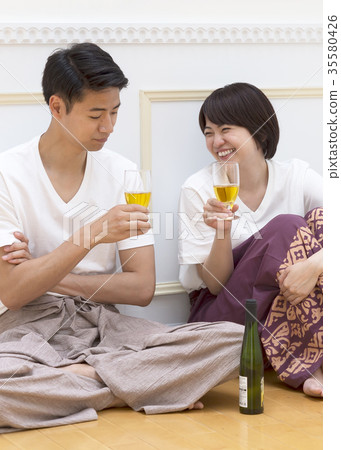 A couple sitting on the floor and tilting the glass 35580426