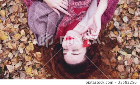 Attractive young woman with red hair lies over dry 35582256