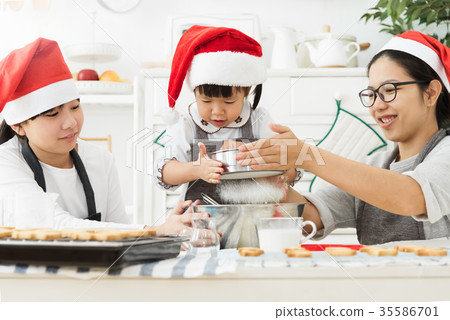 Happy Asian family wear Santa hats sprinkling the dough with flo Happy Asian family wear Santa hats sprinkling the dough with flo 35586701