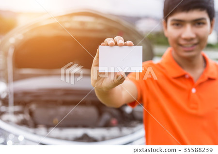 Aian man showing/holding blank of white paper or business card in front of blur damaged car. For car rent or car business Aian man showing/holding blank of white paper or business card in front of blur damaged car. For car rent or car business 35588239