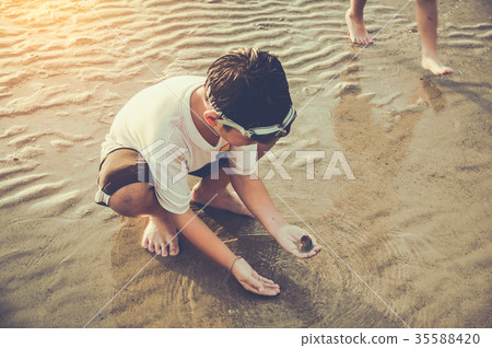 Asian child has fun digging in the sand.  35588420